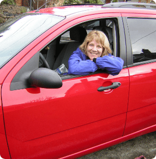 A smiling woman in a red car